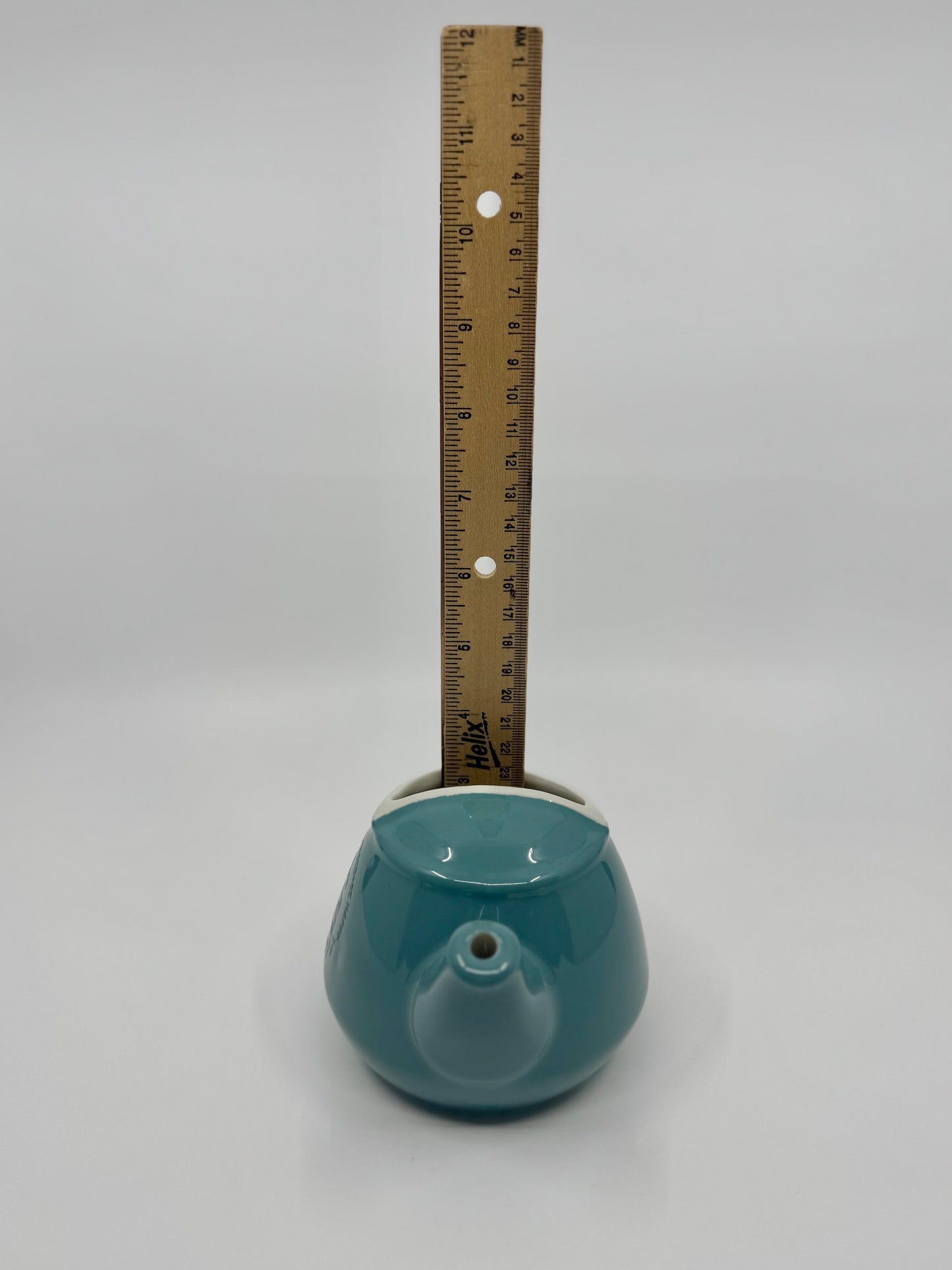 Teal ceramic object with a ruler for scale on a gray background