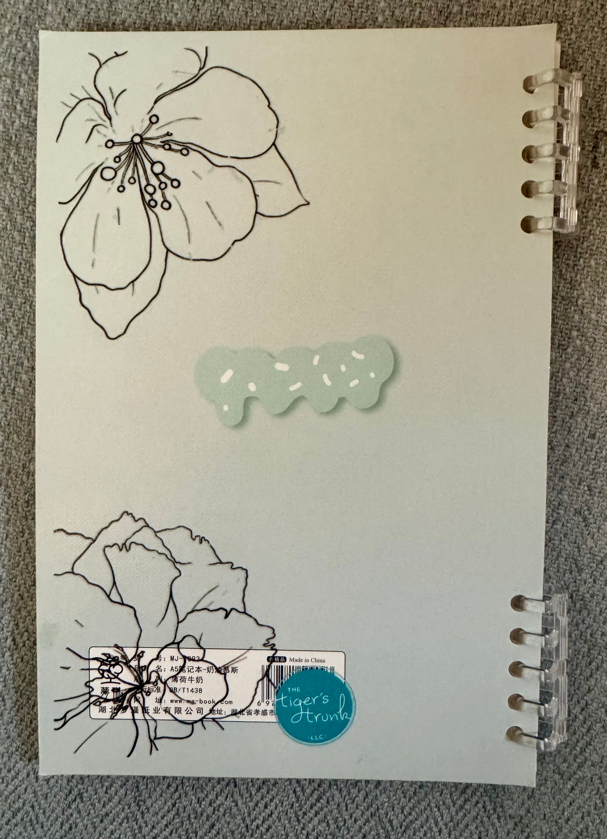 Back cover of Endless Lists of Shit to Do lined journal with minimalist floral line art and clear disc binding on a neutral textured background.