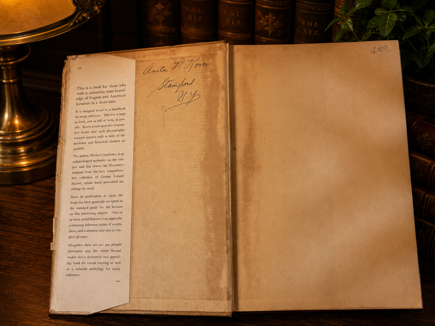 Open book with text and a signature on a wooden surface with books in the background