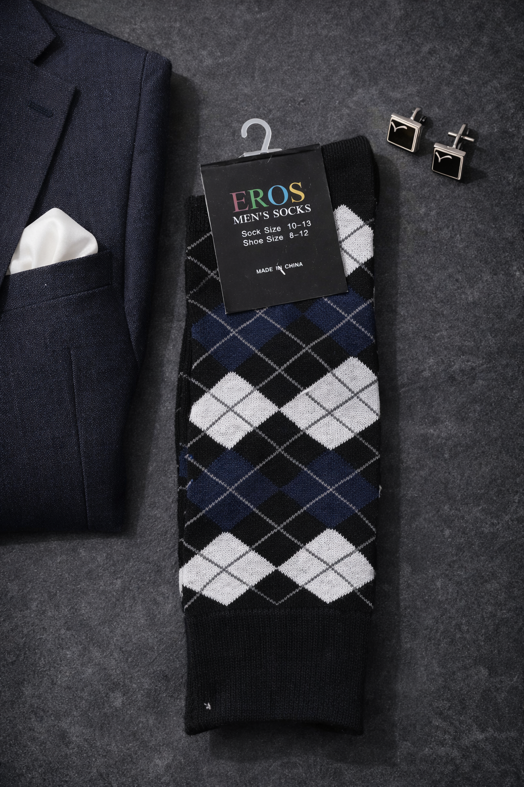EROS men’s argyle crew socks in black, navy blue, and white diamond pattern with retail hang tag showing sock size 10–13 and men’s shoe size 8–12, styled in a formal flatlay with a navy suit jacket and black square cufflinks.