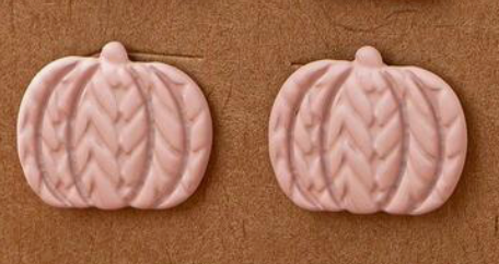 Two pink pumpkin-shaped earrings on a brown background