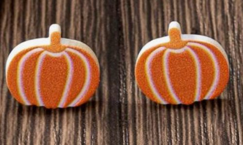 Pumpkin-shaped earrings on a wooden background
