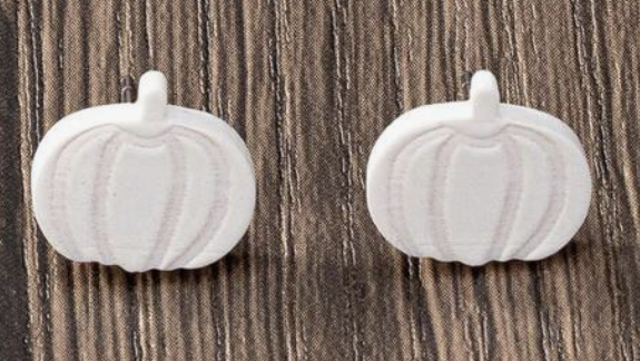 White pumpkin-shaped earrings on a wooden background