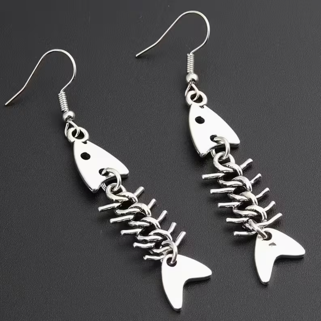 Silver fishbone pendant earrings with dangling skeleton fish design on dark background
