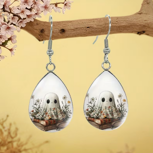 Teardrop earrings featuring a cute white ghost sitting on vintage books surrounded by delicate wildflowers
