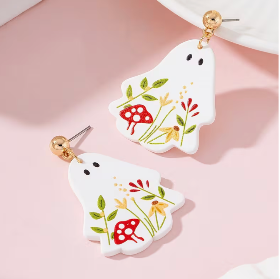 White ghost dangle earrings decorated with colorful mushrooms, greenery and wildflowers with gold-tone posts.