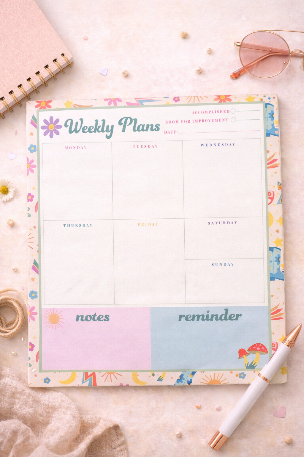 Floral weekly planner pad with pastel colors and sections for each day, notes, and reminders on a styled desk