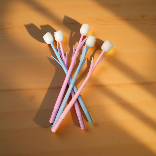 Pastel tulip flower pens arranged on a wooden table with soft natural lighting
