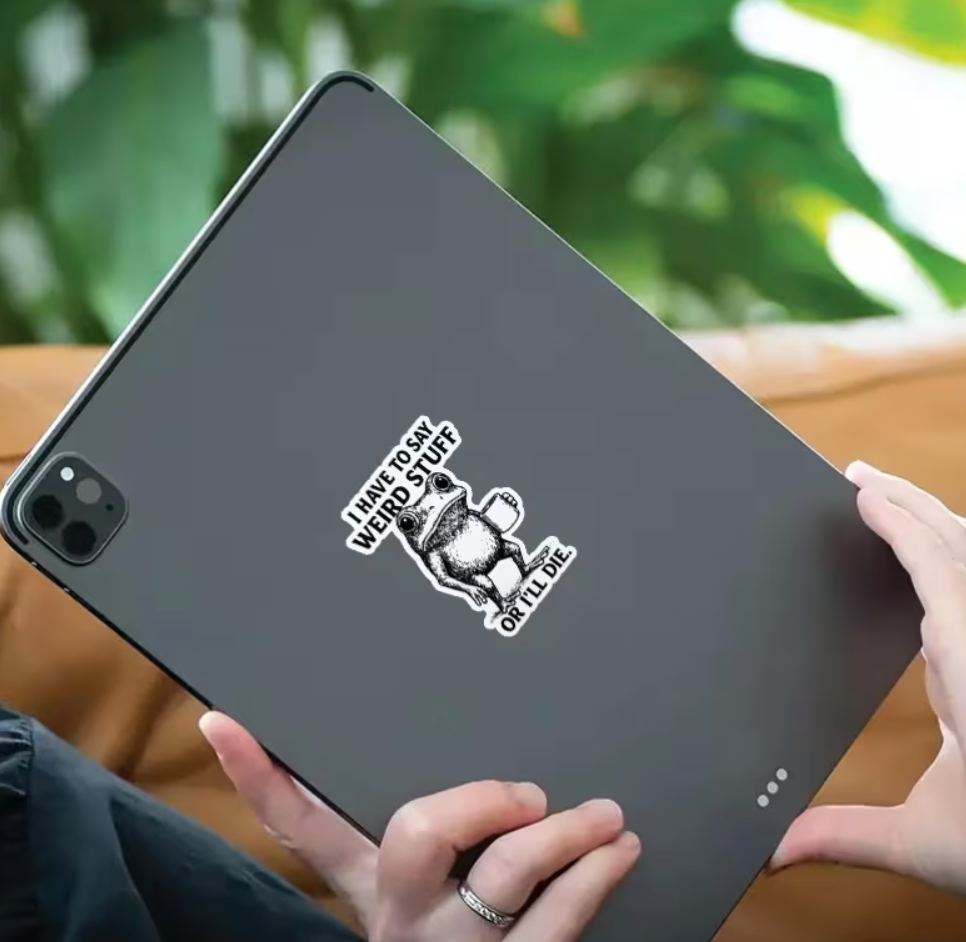 Funny black and white frog holding a coffee mug sticker displayed on a tablet