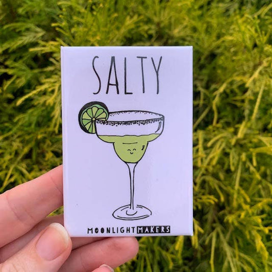 Funny salty margarita magnet with cute cocktail illustration held in hand outdoors