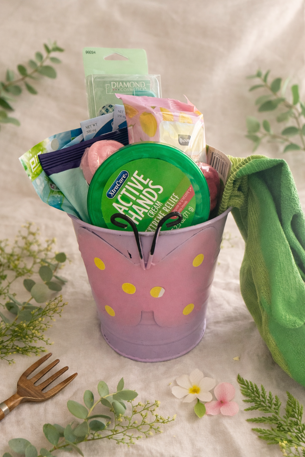 Pink bucket with green lid filled with cleaning supplies on a light background