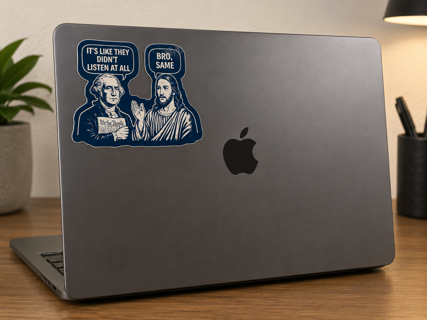 Laptop with a sticker of two figures and text on a desk