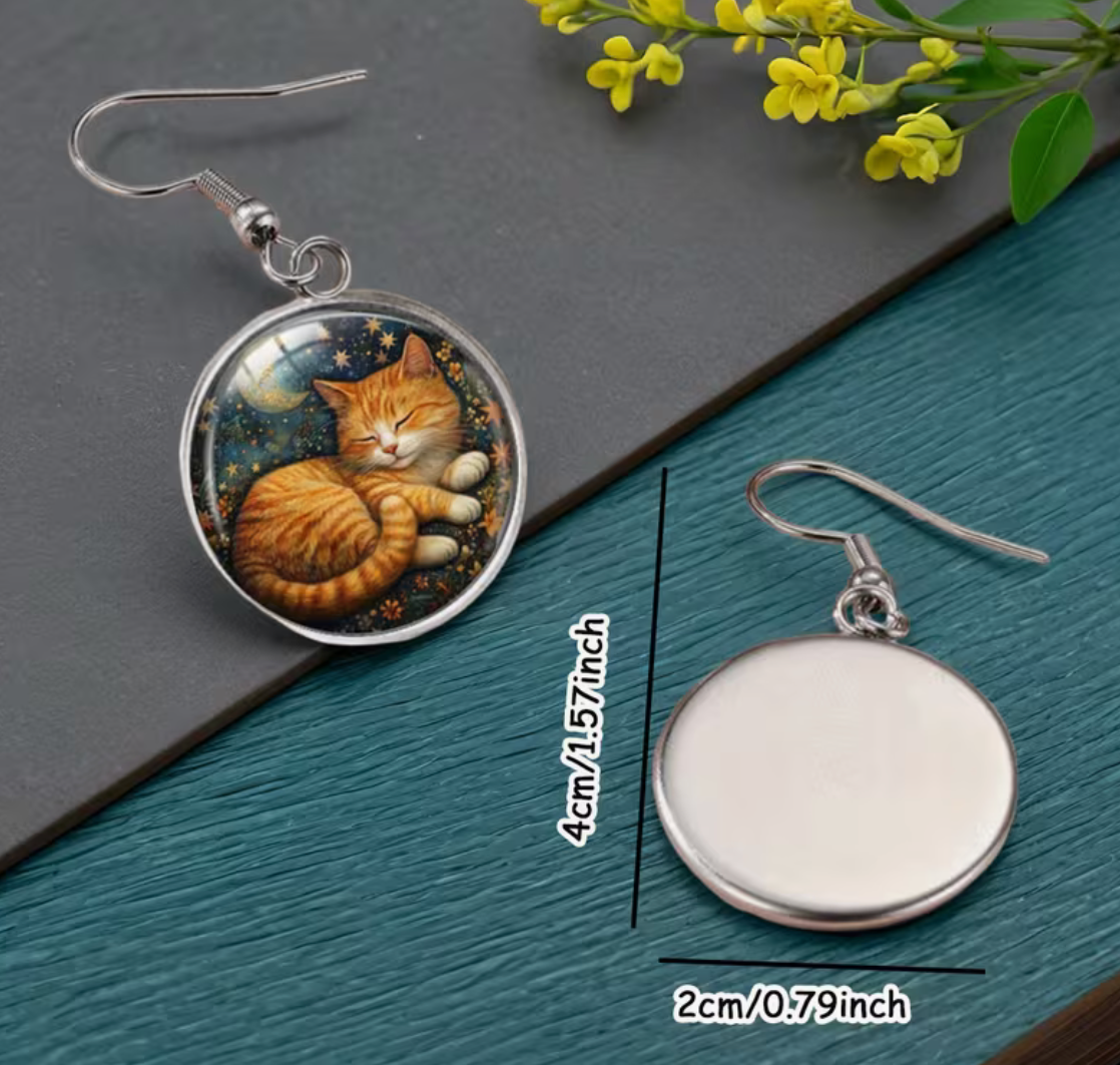 Cat-themed earrings on a dark surface with measurements indicated.
