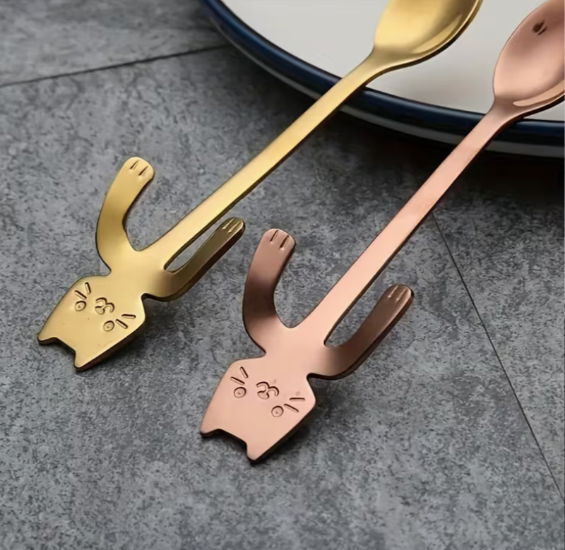 Gold and rose gold stainless steel kawaii cat spoons with cat face detail and hooked paws for hanging on mug rims.