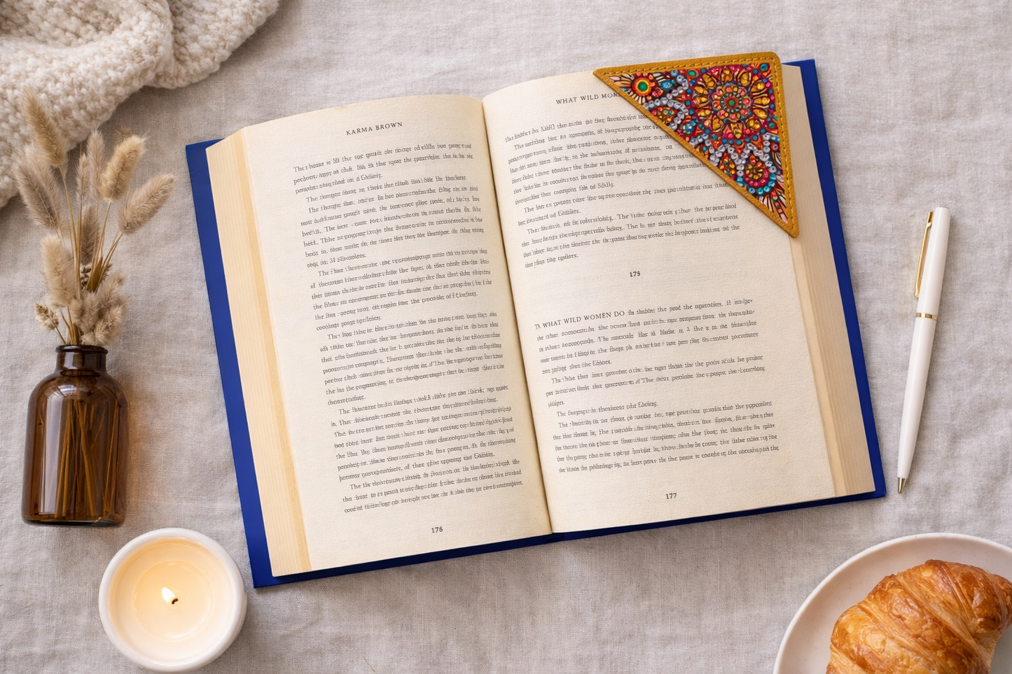 Open book flatlay with candle, croissant, and detailed bejeweled vegan leather corner bookmark