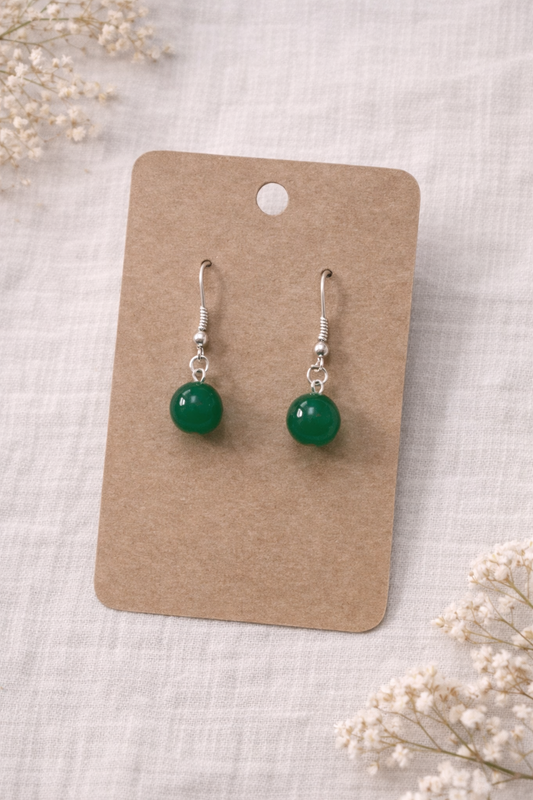 Green ball drop earrings with silver tone hooks displayed on a neutral jewelry card