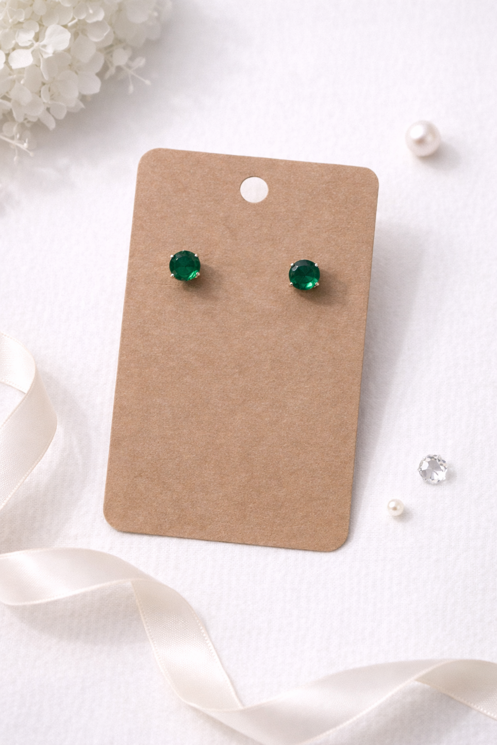 Green cubic zirconia stud earrings displayed on kraft jewelry card