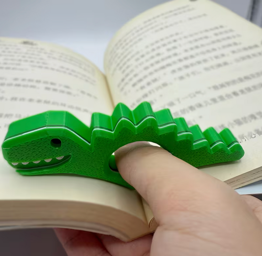 hand using green dinosaur thumb page holder for comfortable one-handed reading