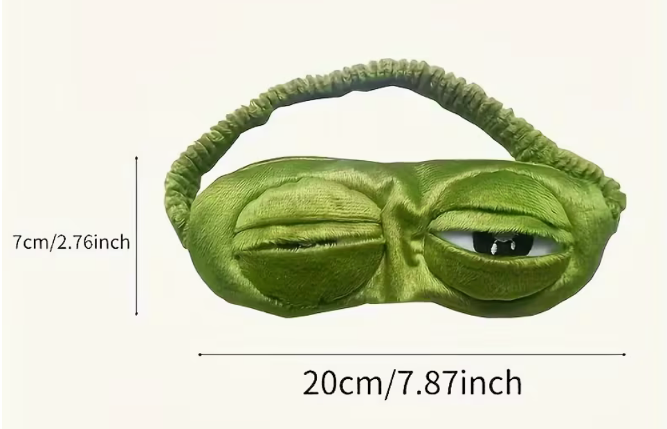 Green plush frog sleep mask with one closed eye and one open eye, measuring approximately 7.87 by 2.76 inches.