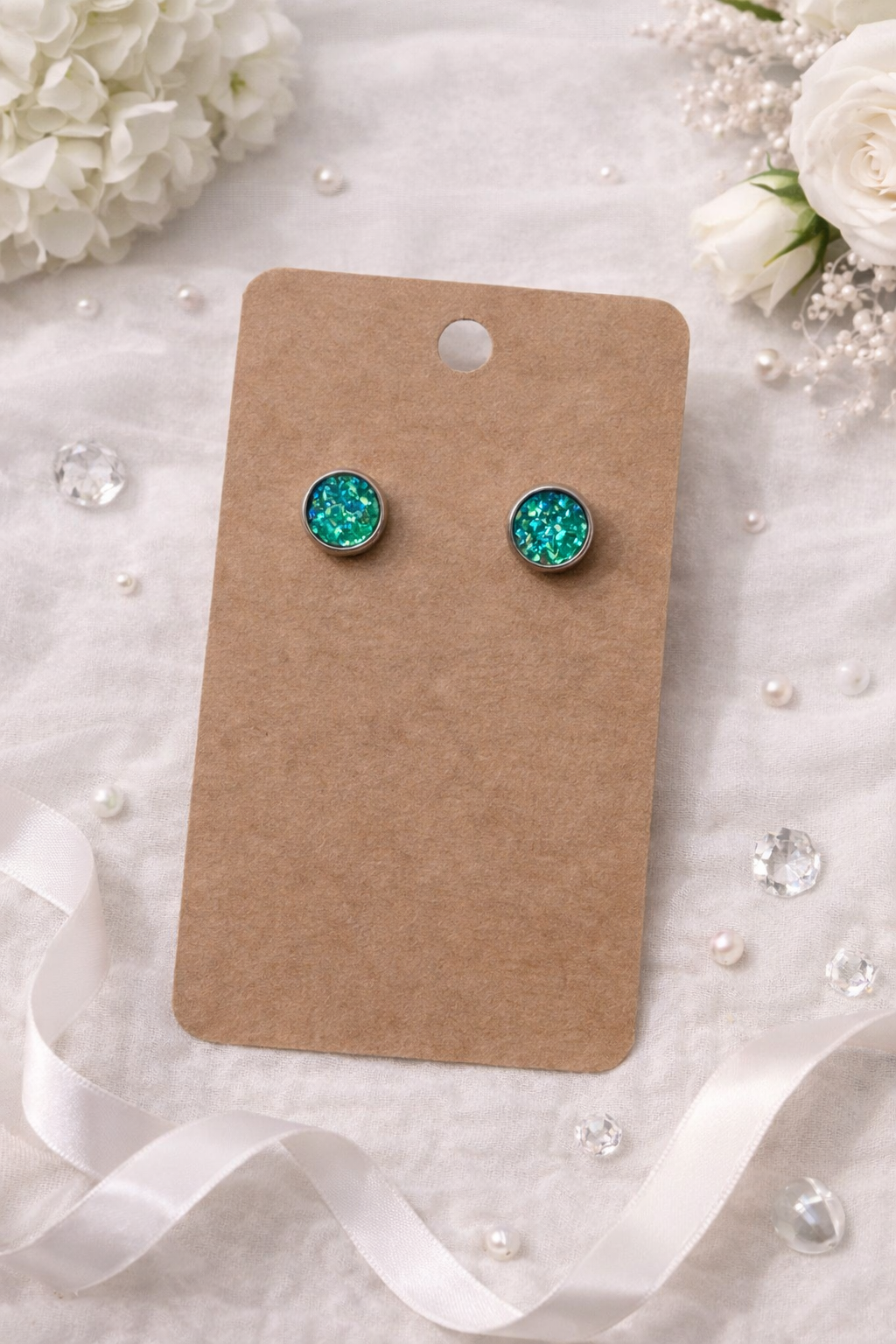 Green glitter stud earrings with round silver tone setting displayed on a jewelry card