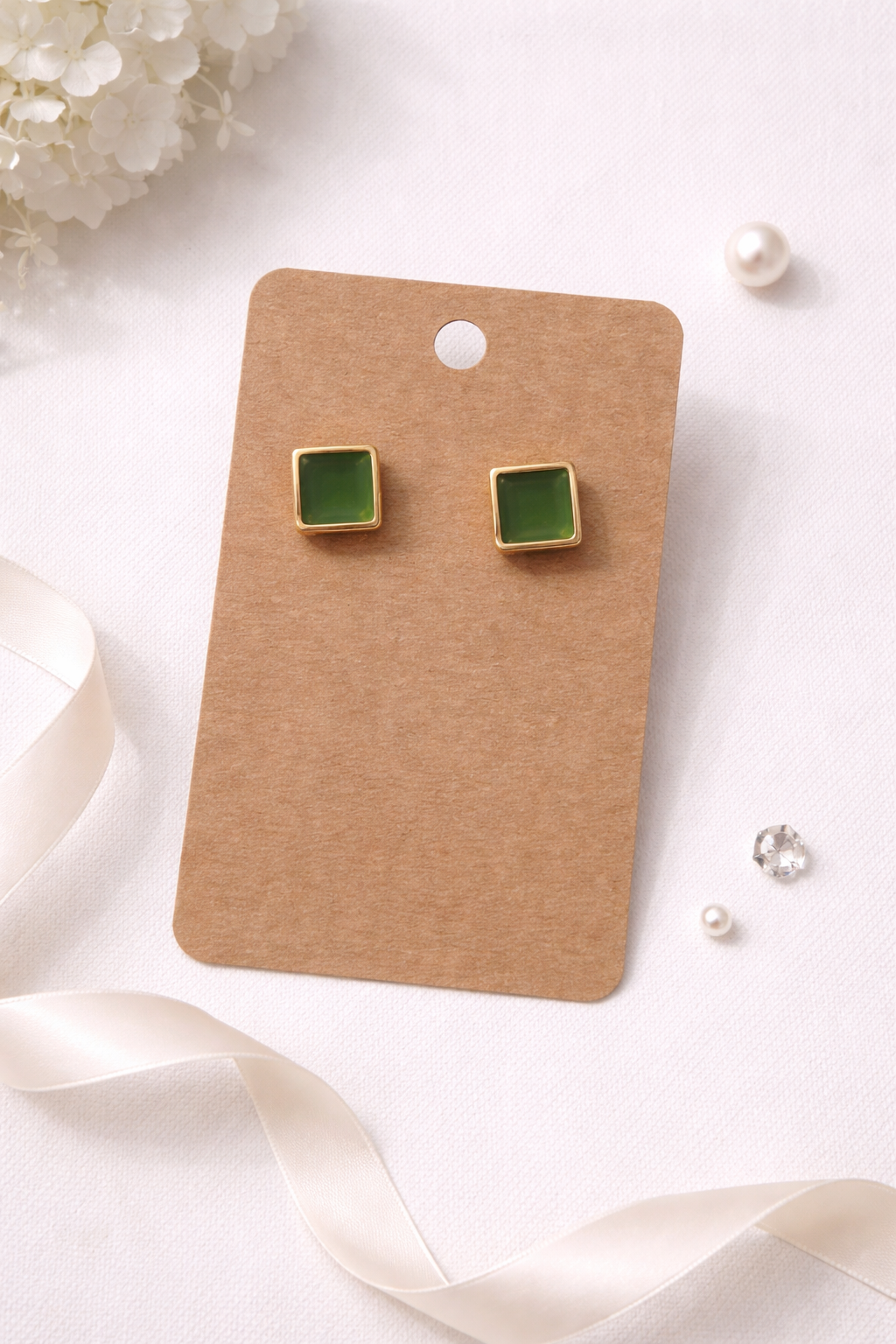 Green square stud earrings with gold frame displayed on jewelry card