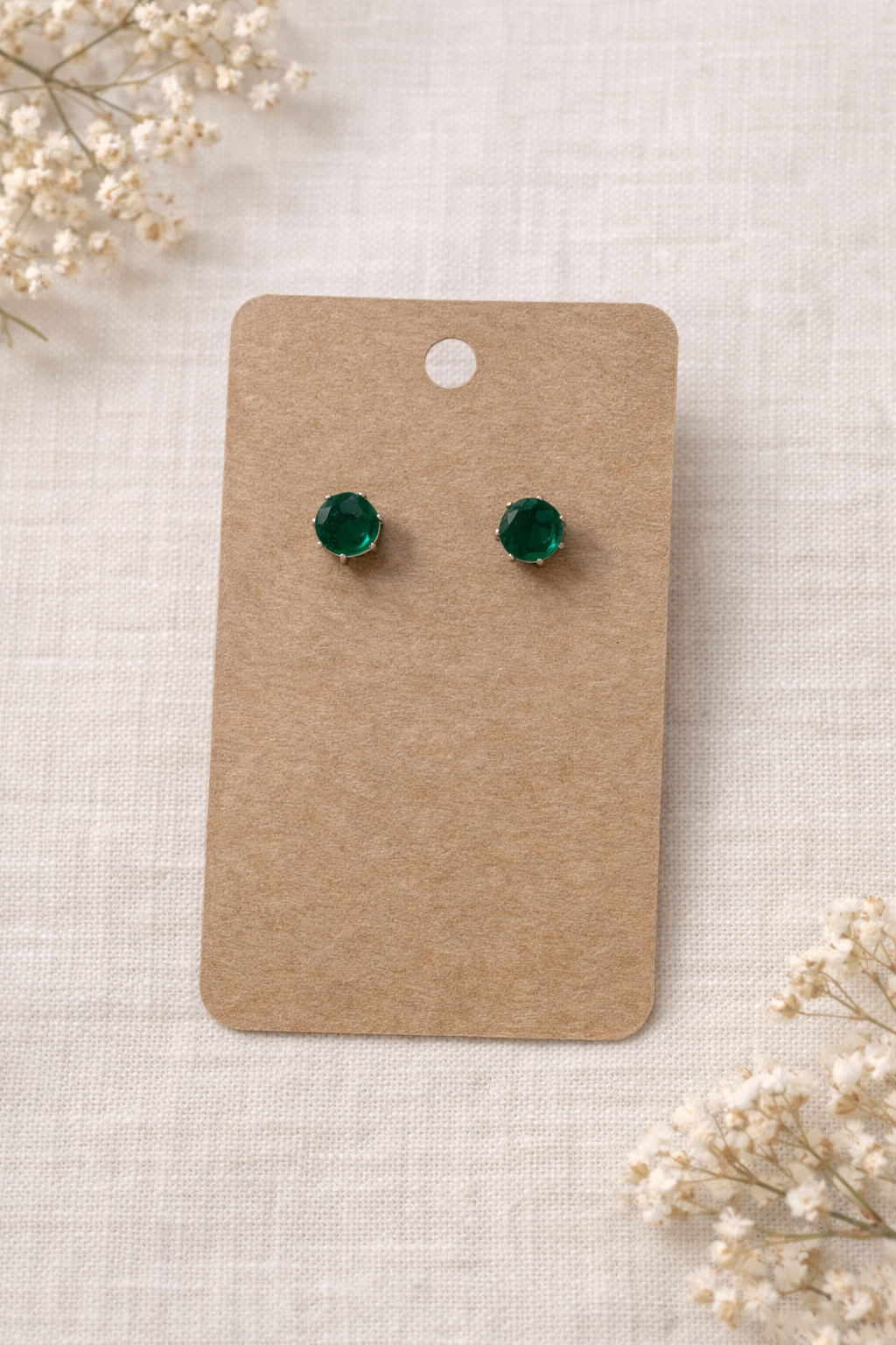 Green stud earrings with silver tone setting displayed on a neutral jewelry card with a soft background