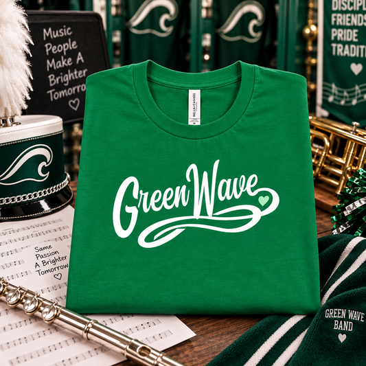 A folded green crewneck t-shirt with 'Green Wave' printed in white script across the front, styled on a wooden table with band instruments and a green-and-white striped bandana in the background.
