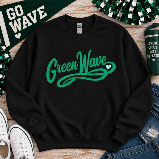 A black crewneck sweatshirt with a green 'Green Wave' graphic printed on the front, styled in a flat lay with St. Patrick's Day themed props including a green 'GO WAVE' banner, white sneakers, denim, and a green tumbler on a wooden surface.