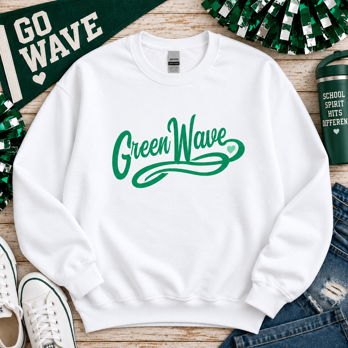 A white crewneck sweatshirt with 'Green Wave' printed in green script across the chest, styled in a flat lay with a green 'GO WAVE' banner, cheerleaders, jeans, sneakers, and a green tumbler.