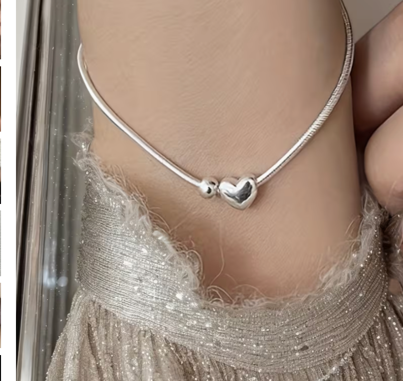 Close up of dainty heart charm bracelet worn on wrist with silver chain