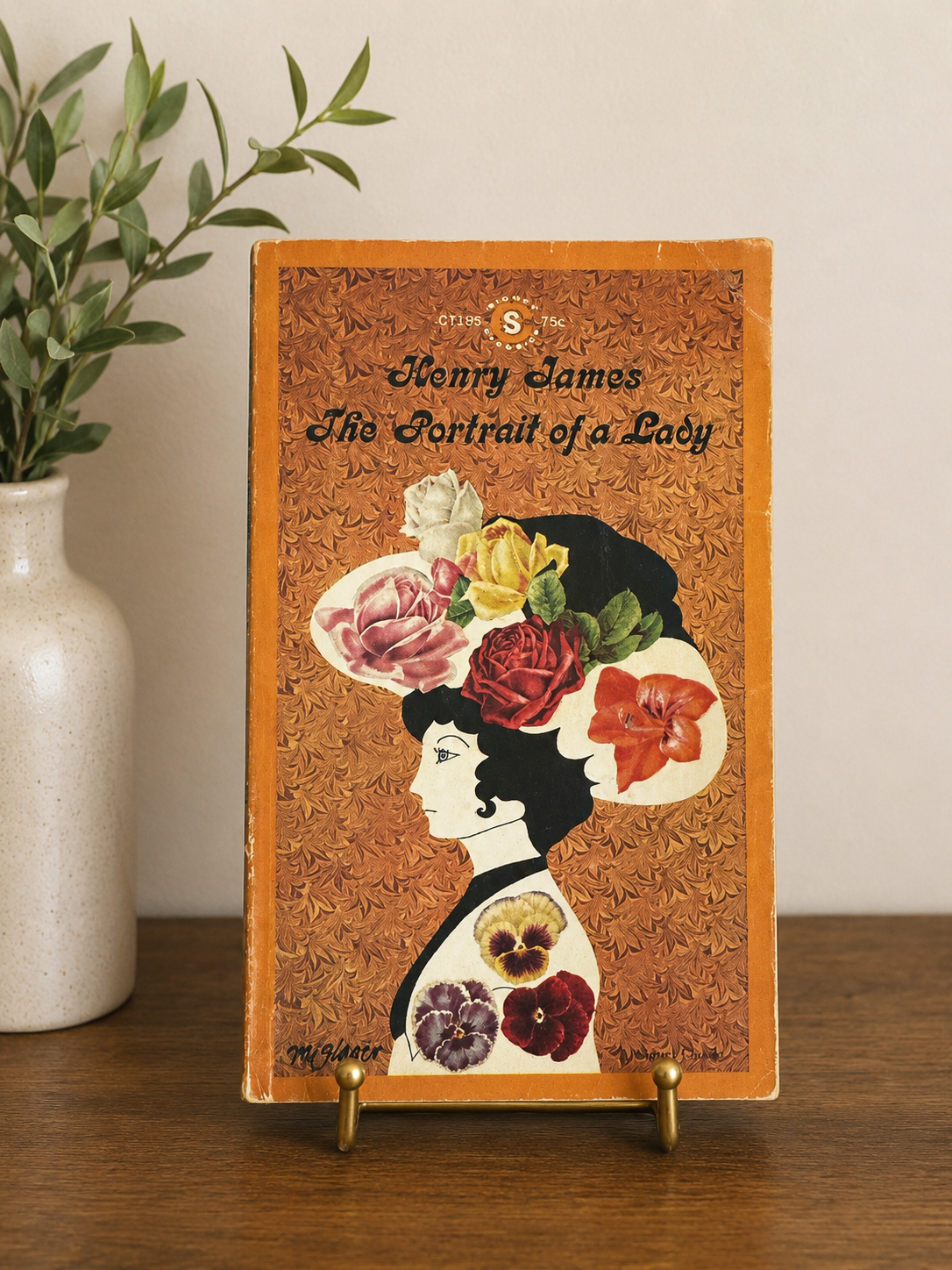 Vintage 1964 Signet Classics paperback edition of The Portrait of a Lady by Henry James displayed on a brass book stand