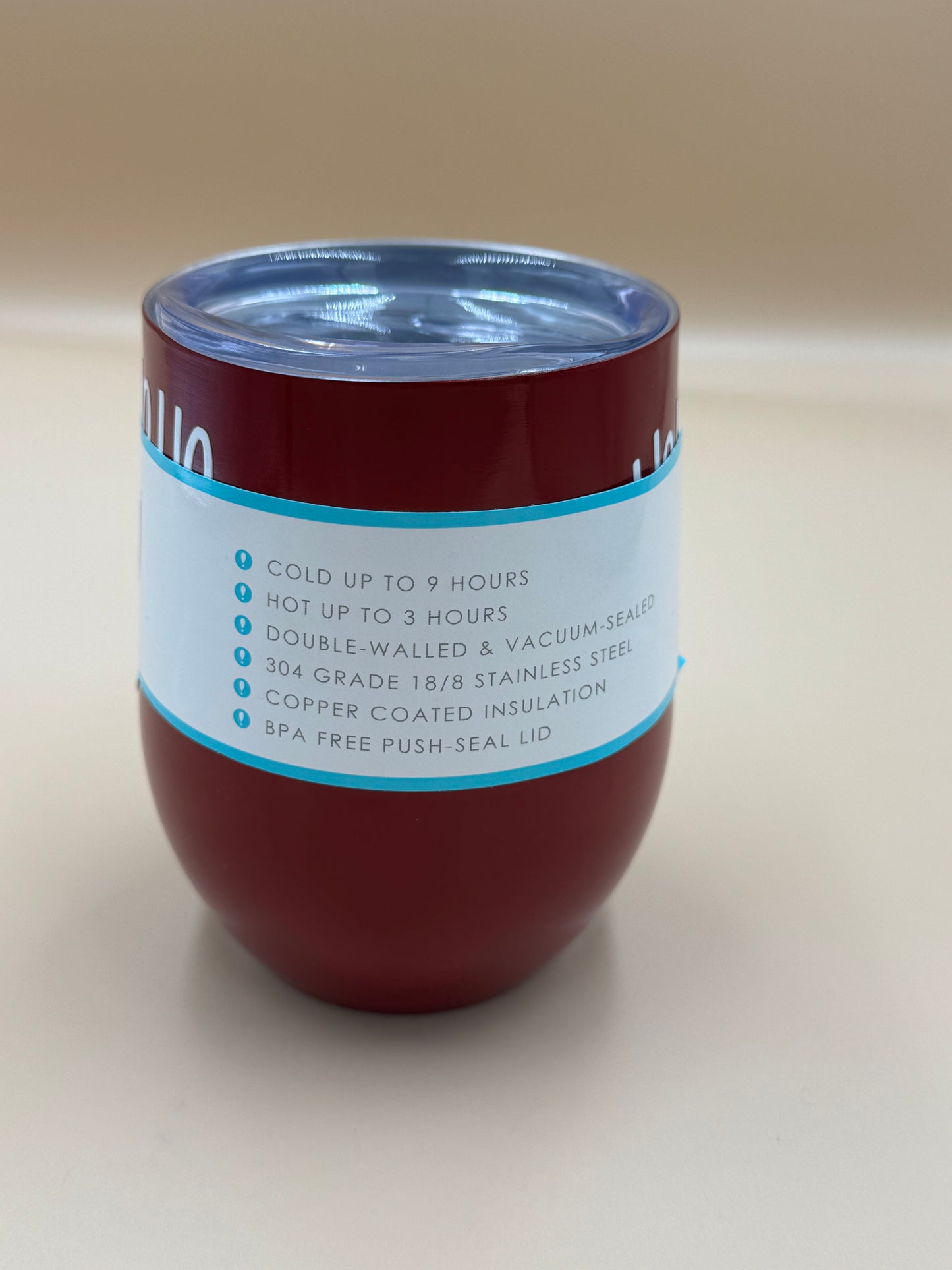 Red insulated tumbler with a label on a beige background