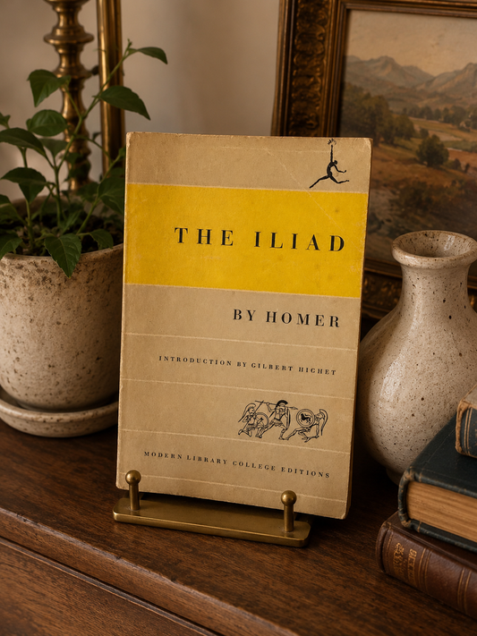 Book titled 'The Iliad' by Homer on a wooden surface with decorative items.