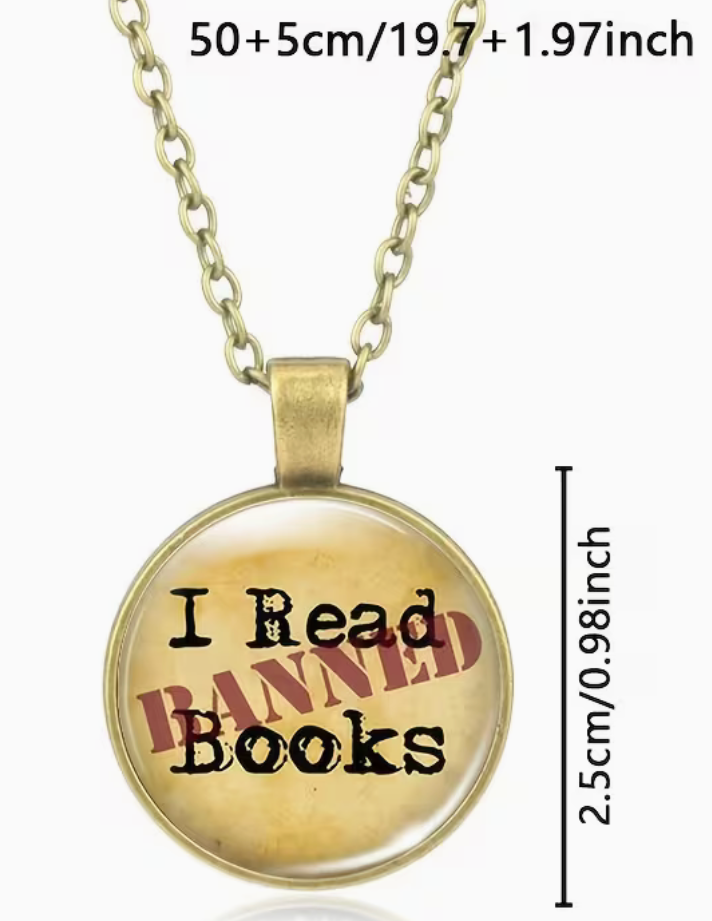 A round pendant necklace with a gold-tone chain and bezel, featuring the text 'I Read Banned Books' in black over a yellowed book-cover-like background. Measurement text and a vertical dimension marker are overlaid on the image.