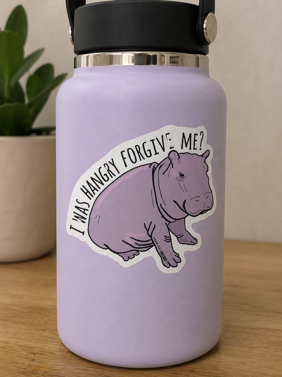 Purple hippo die cut sticker with the phrase "I Was Hangry Forgive Me" displayed on a lavender water bottle.