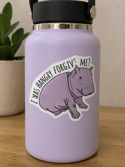 Purple hippo die cut sticker with the phrase "I Was Hangry Forgive Me" displayed on a lavender water bottle.