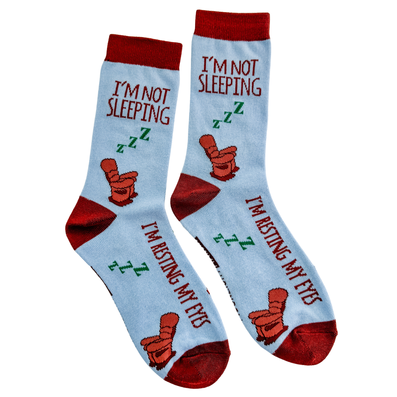 Pair of light blue novelty crew socks with red heels and cuffs, a brown recliner chair design, and the phrases I’m not sleeping and I’m resting my eyes on a white background.