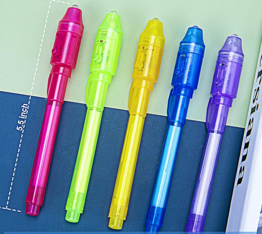 Five invisible ink spy pens displayed on a notebook showing 5.5-inch length