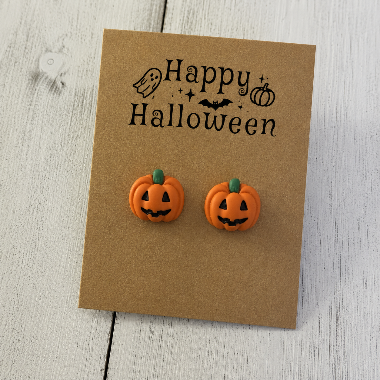 Orange jack-o-lantern resin stud earrings with black faces and green stems for Halloween