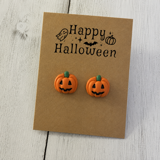 Orange jack-o-lantern resin stud earrings with black faces and green stems for Halloween