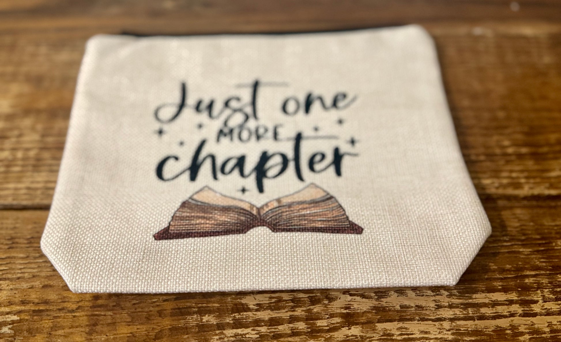 A 7"x8.5" accessories pouch featuring the phrase Just One More Chapter, perfect for storing pencils, cosmetics, or bookish essentials.