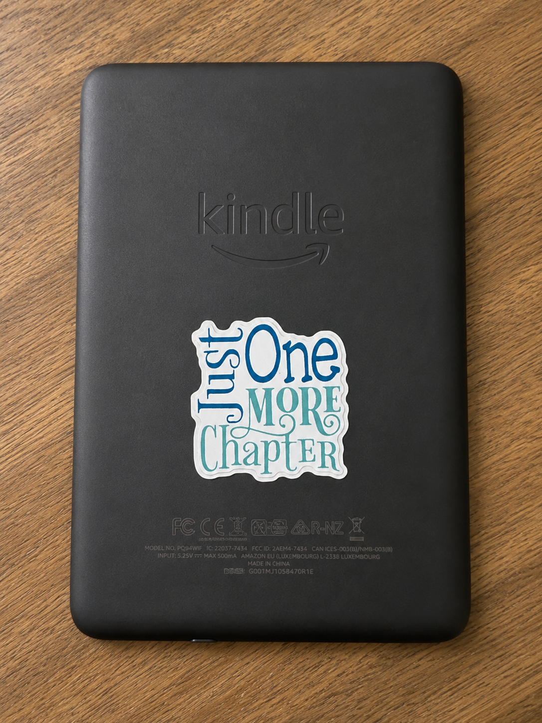 Just One More Chapter die cut vinyl sticker displayed on the back of a Kindle e-reader.