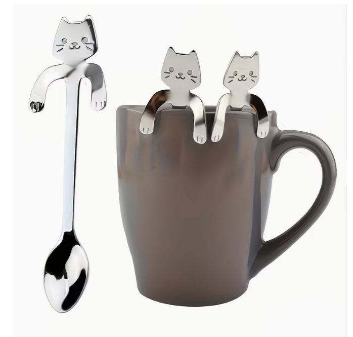 Stainless steel kawaii cat spoon hooked onto the rim of a gray mug alongside two identical cat spoons.