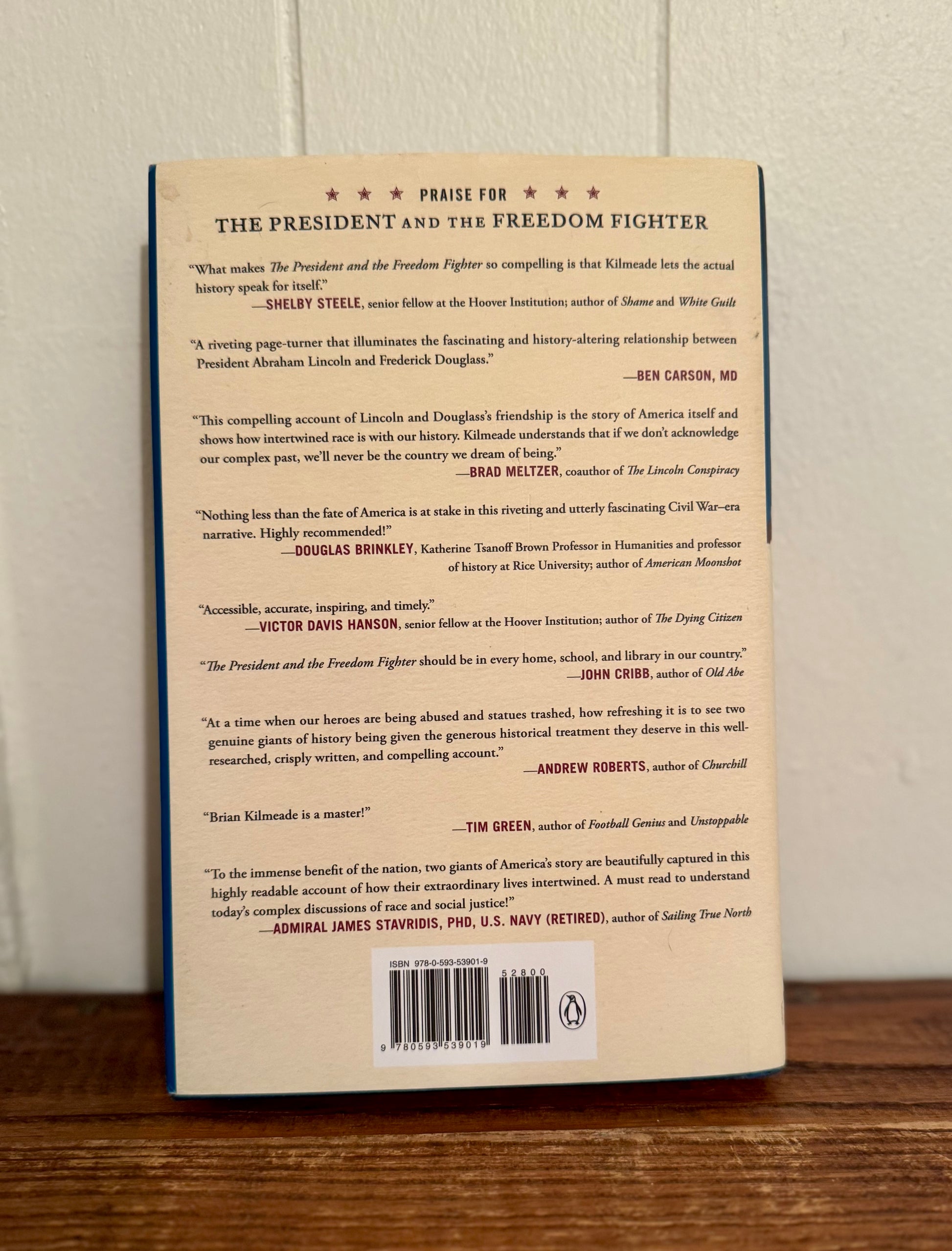 Back cover of a book with text and a barcode on a wooden surface.