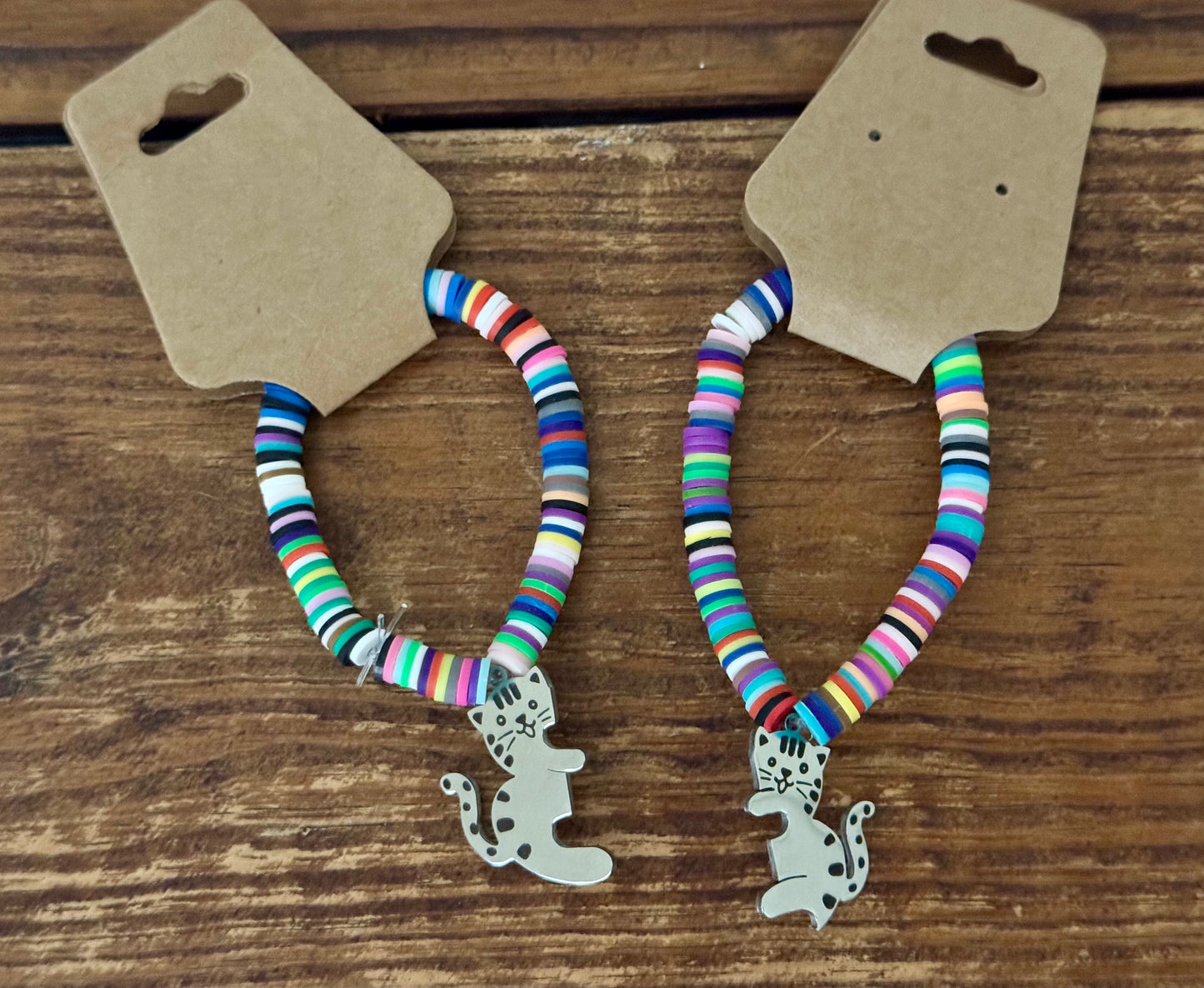 Two colorful striped bracelets with dog charms on a wooden surface