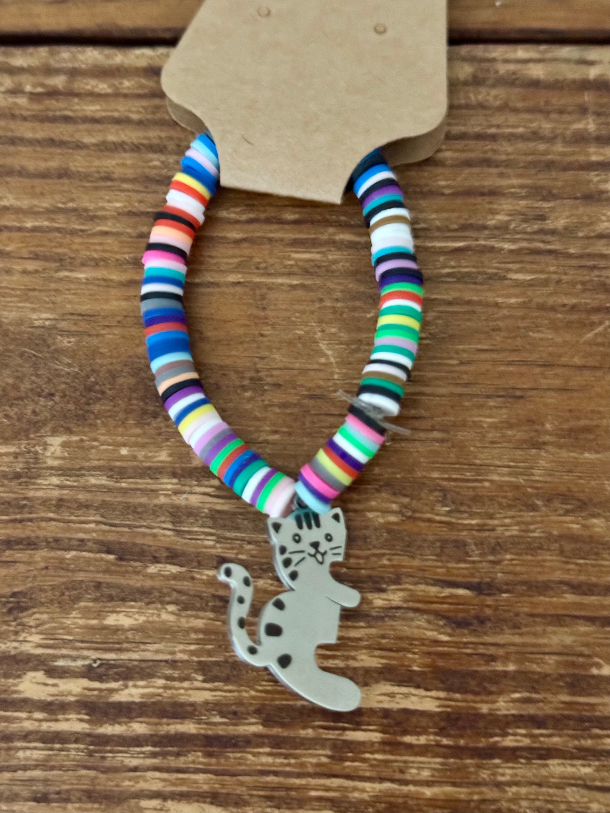 Colorful beaded bracelet with a cat charm on a wooden surface
