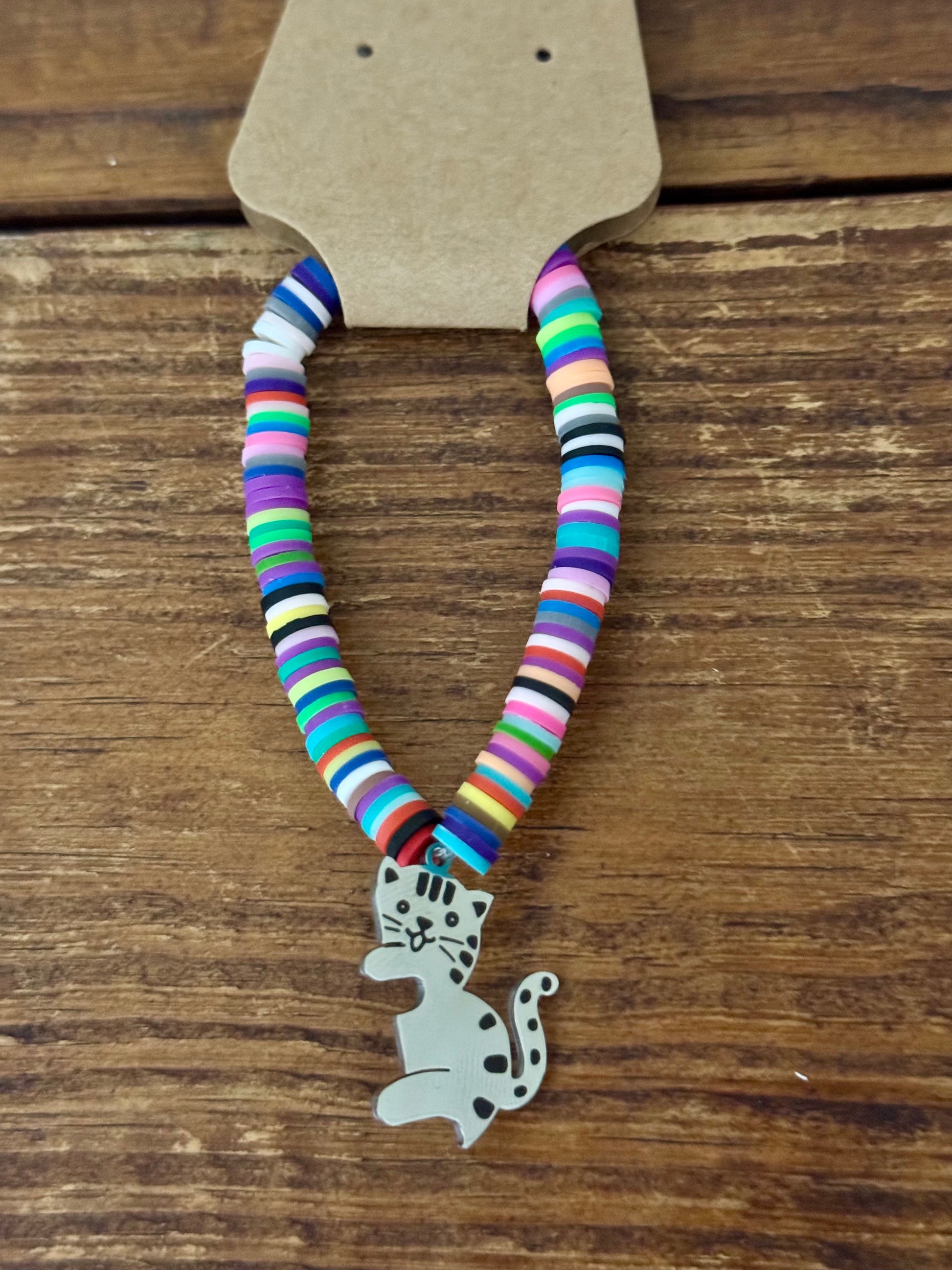 Colorful striped bracelet with a cat charm on a wooden surface