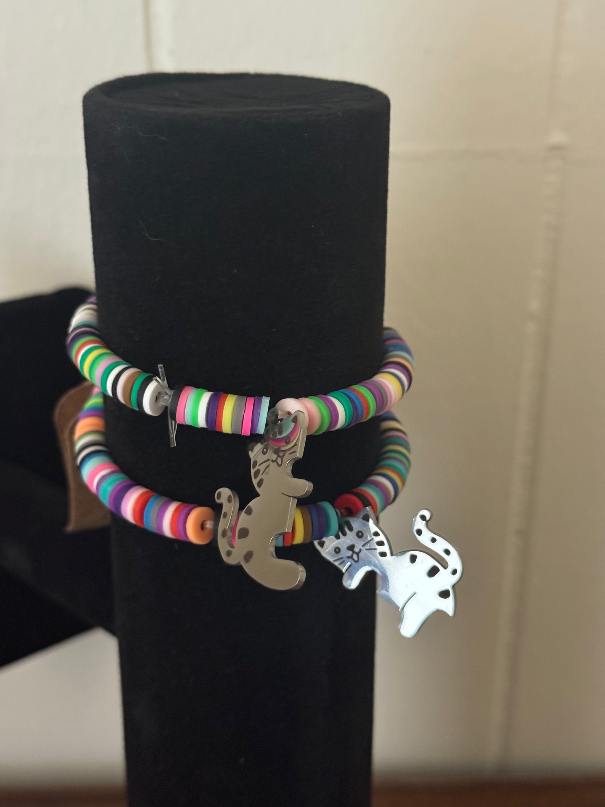 Colorful bracelet with charms on a black stand against a neutral background