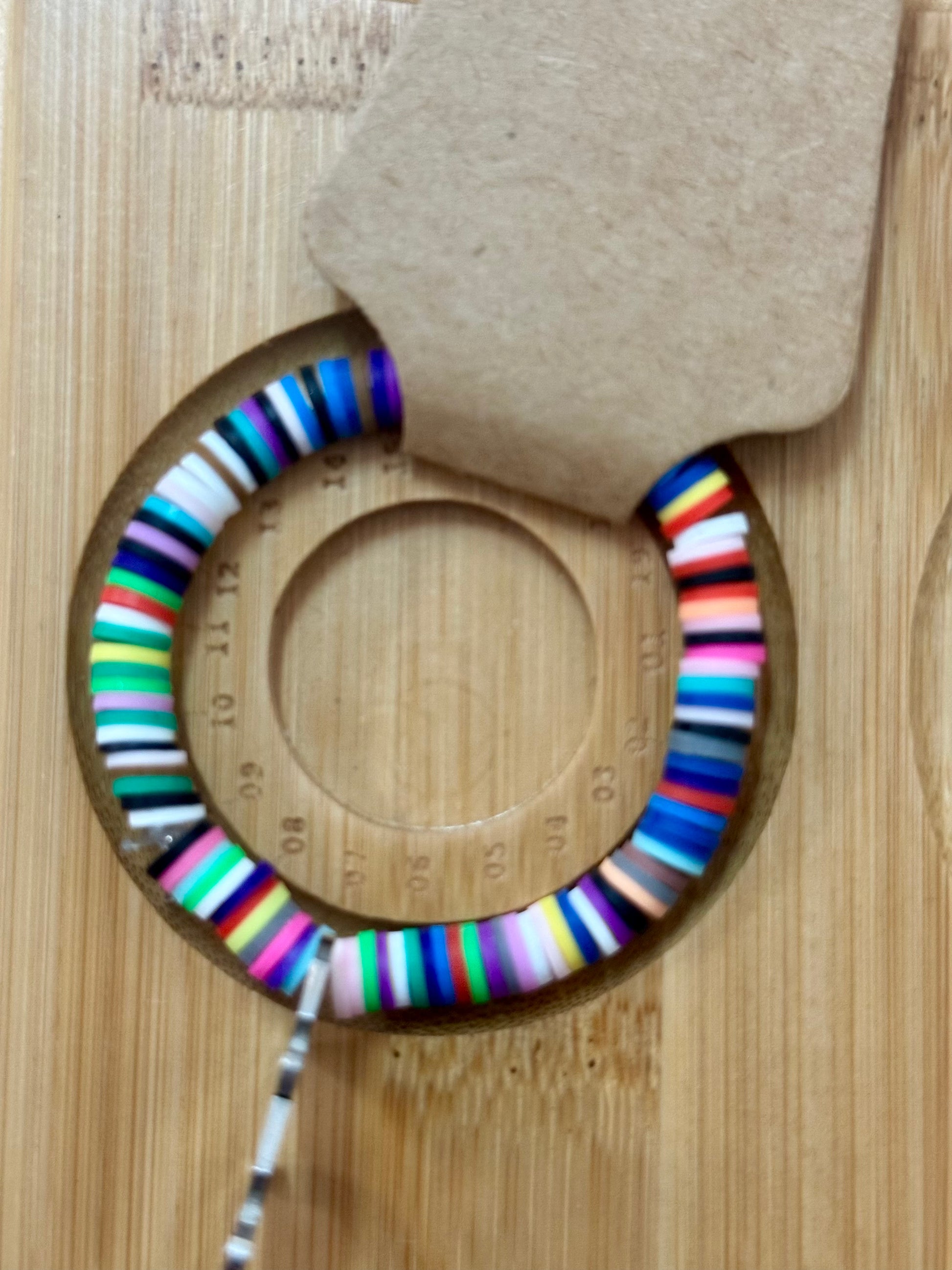 Colorful striped earrings on a wooden surface with a cardboard backing.
