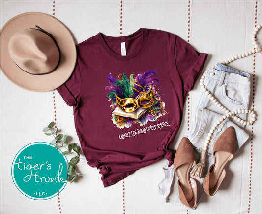 Maroon t-shirt with Mardi Gras-themed design, hat, shoes, and jeans on a white background.